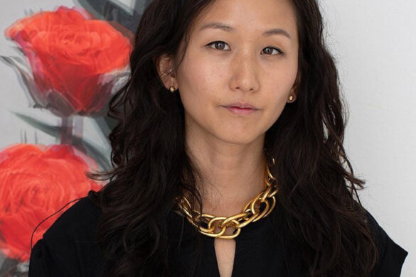A headshot of Jieun Beth. She wears a short sleeve black top and a gold necklace with large chain links. She looks straight at the camera without smiling.