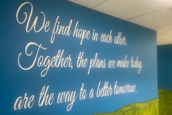 A photograph of mural text that reads, "We find hope in each other. Together, the plans we make today are the way to be a better tomorrow."